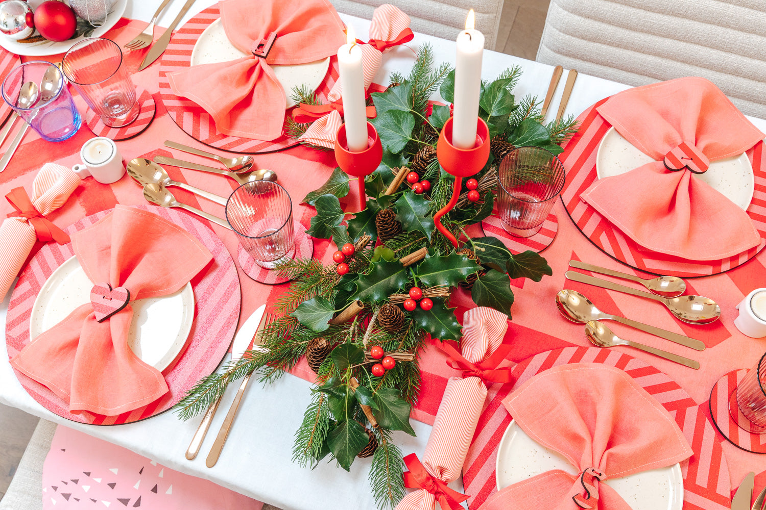 Decorative Christmas table setting with bubblegum pink napkins, candy stripe, pink and red pattered cork placemats and coasters. 