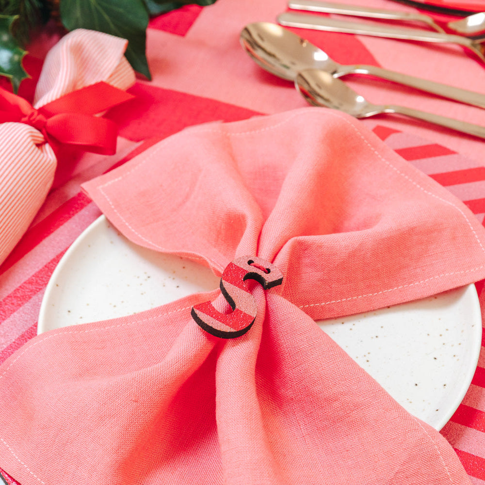 Decorative table setting with pink napkins, gold cutlery and sustainable Christmas cracker.
