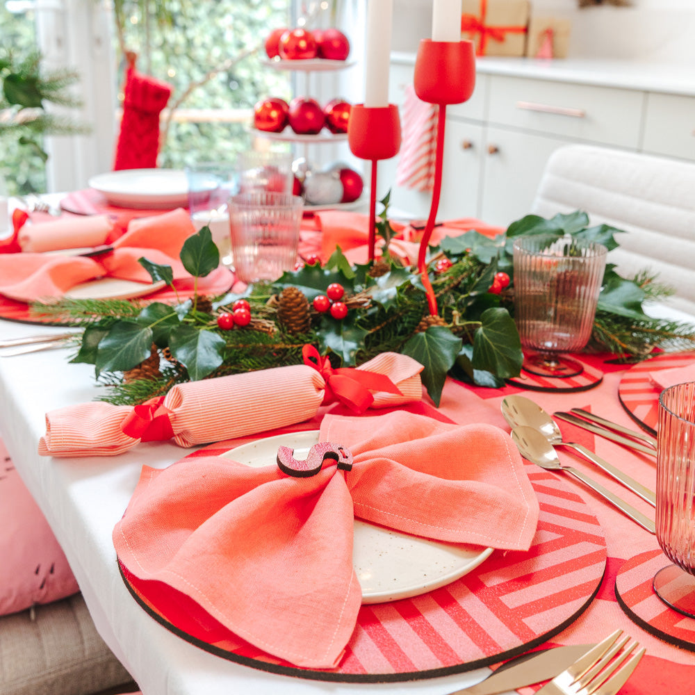 Decorative Christmas table setting with bubblegum pink napkins, candy stripe, pink and red pattered cork placemats and coasters. 