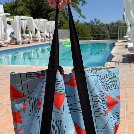 Blue & red patterned travel tote bag being filled with items for a day trip to the beach.