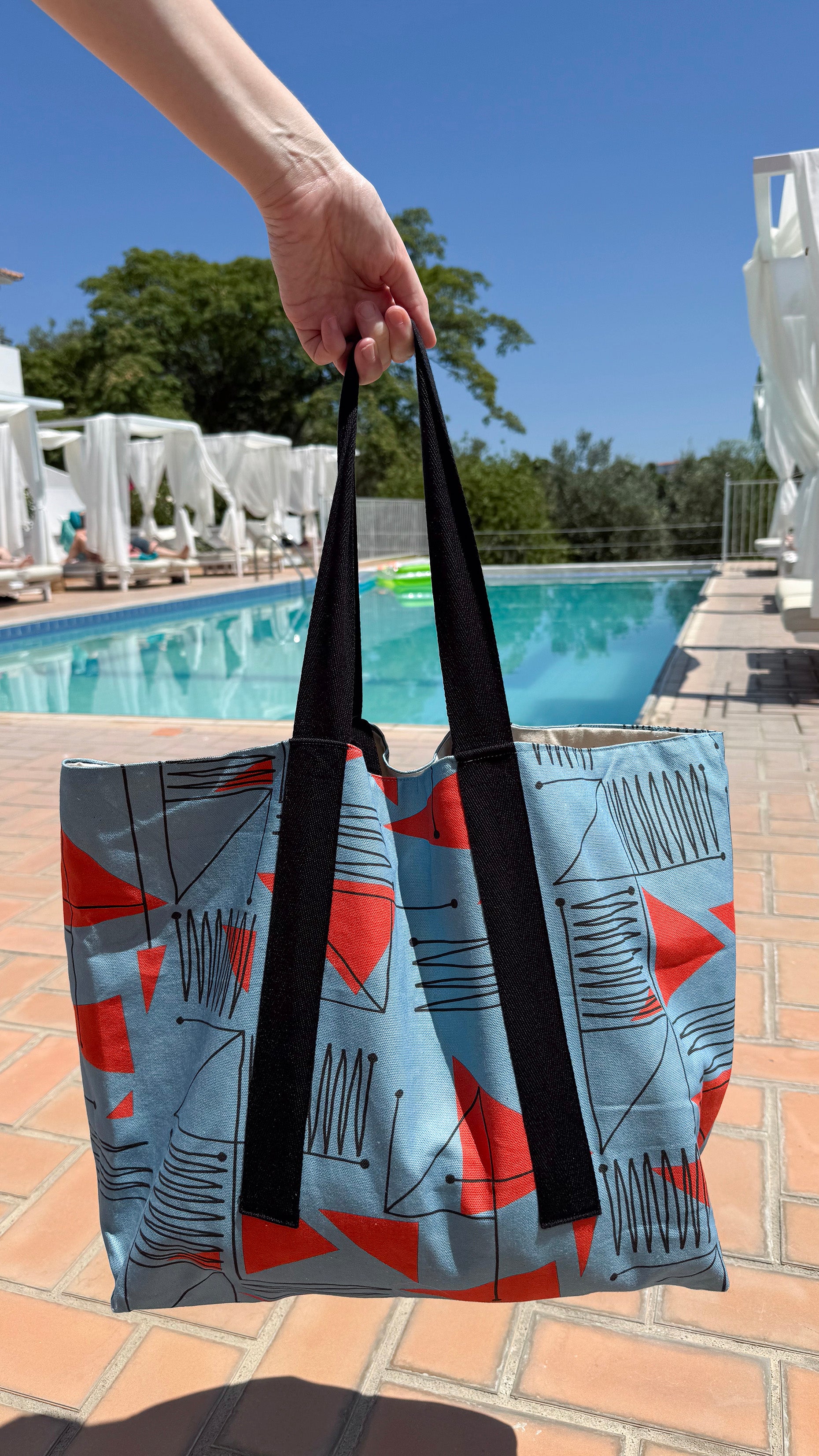 Blue & red patterned travel tote bag being filled with items for a day trip to the beach.